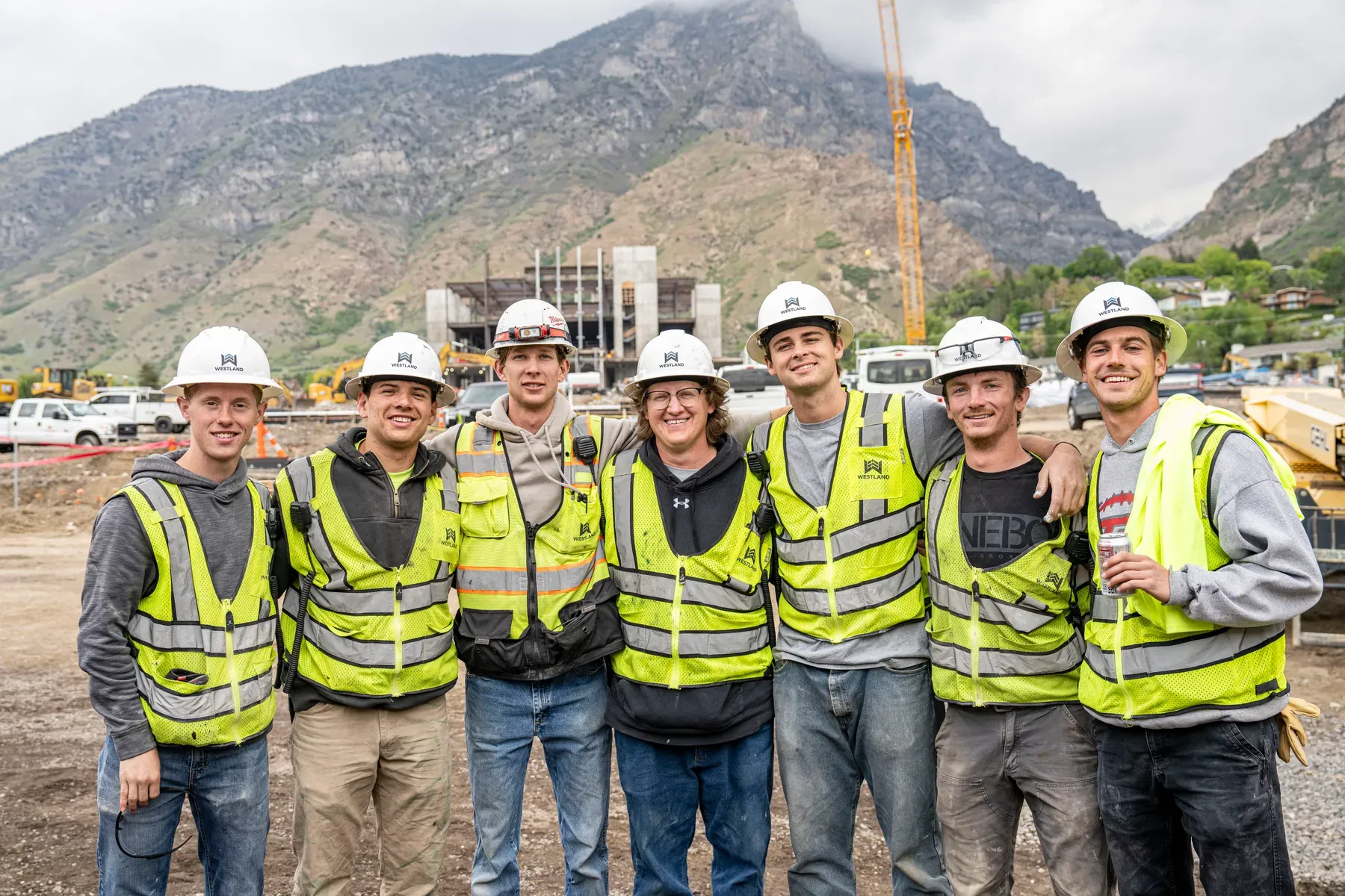 Seven Westland crew members in hard hats and safety vests on a job site below the mountains