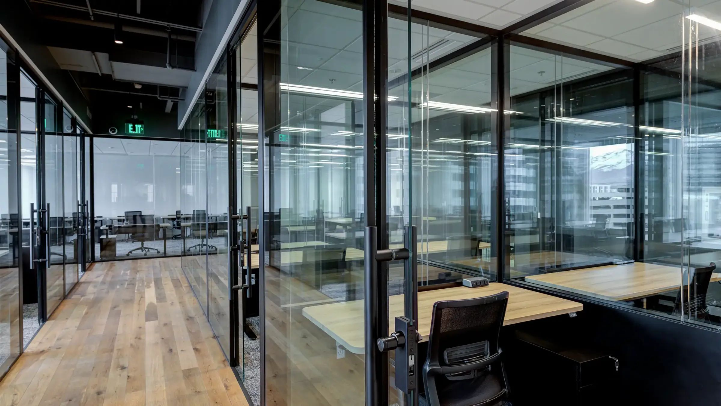 Glass-walled private offices with hardwood corridor