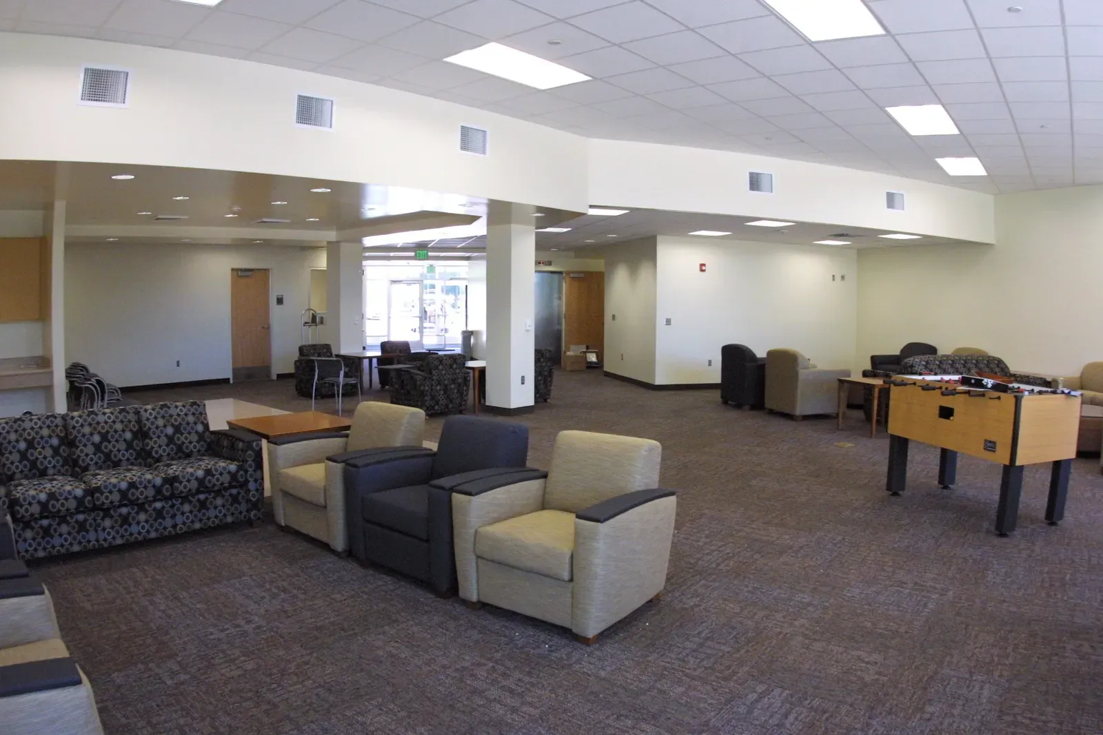 Residence hall lounge with armchairs, sofas and a foosball table.