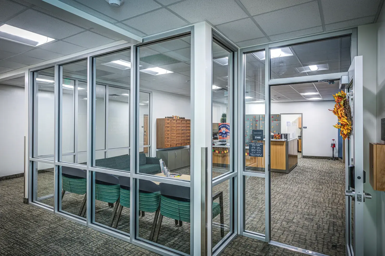 Glass-walled office suite with a reception counter and mailboxes seen through aluminum-framed windows