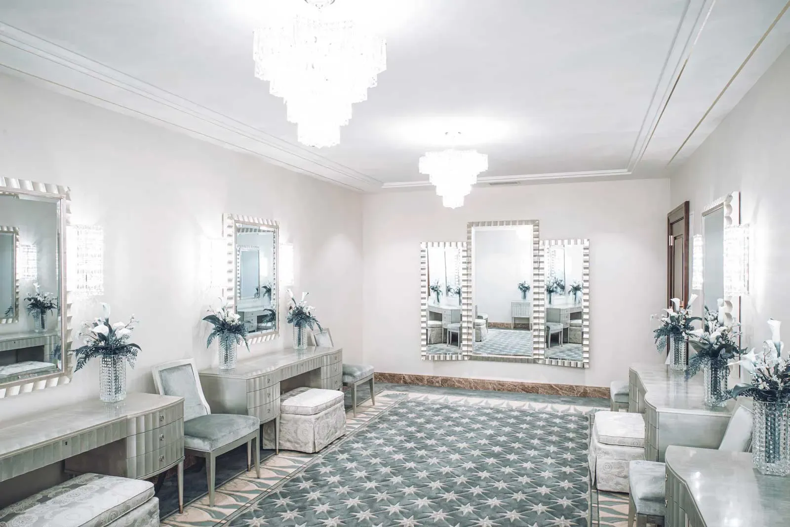 Dressing room with wall mirrors, upholstered stools, vanities, and crystal chandeliers