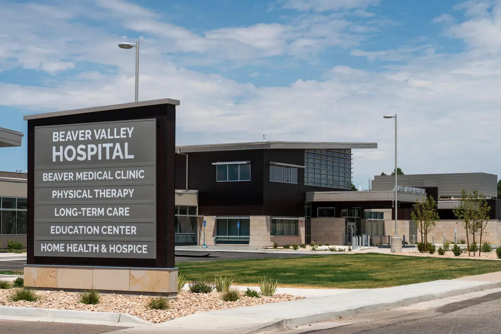 Hospital entrance sign listing Beaver Medical Clinic, Physical Therapy, Long-Term Care, Education Center and Home Health & Hospice, with the building behind.