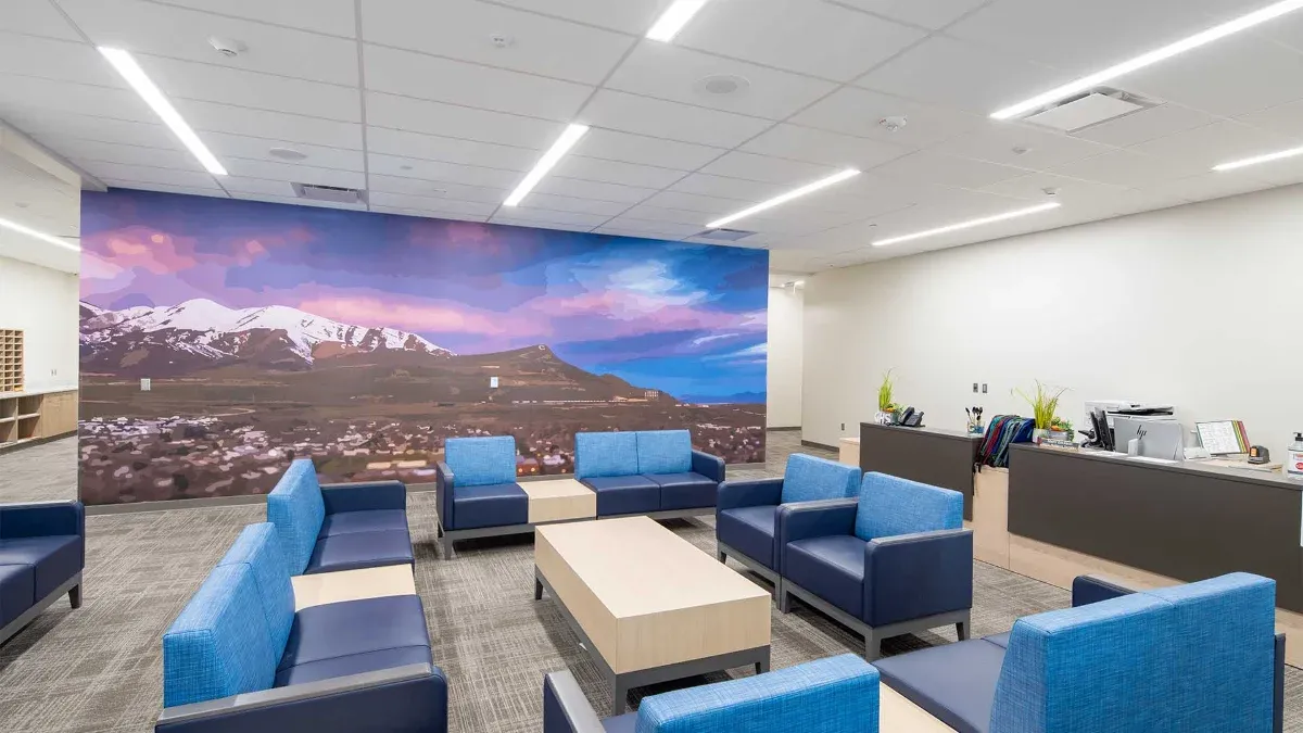 Student lounge with blue upholstered seating in front of a mountain landscape mural
