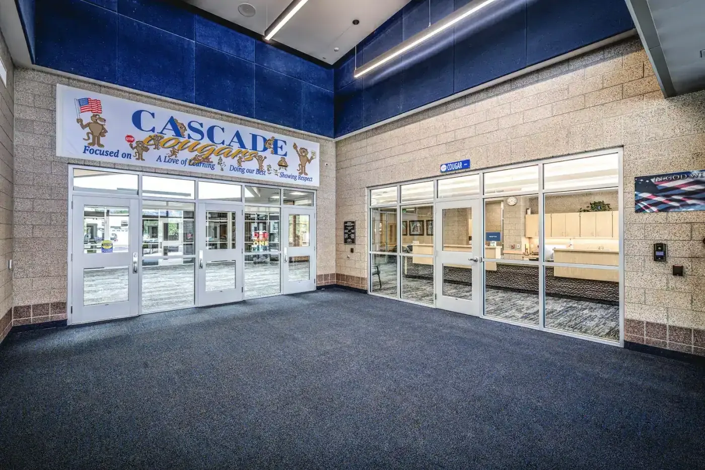 Main entry vestibule with a Cascade banner above glass doors and the main office visible through windows at right.