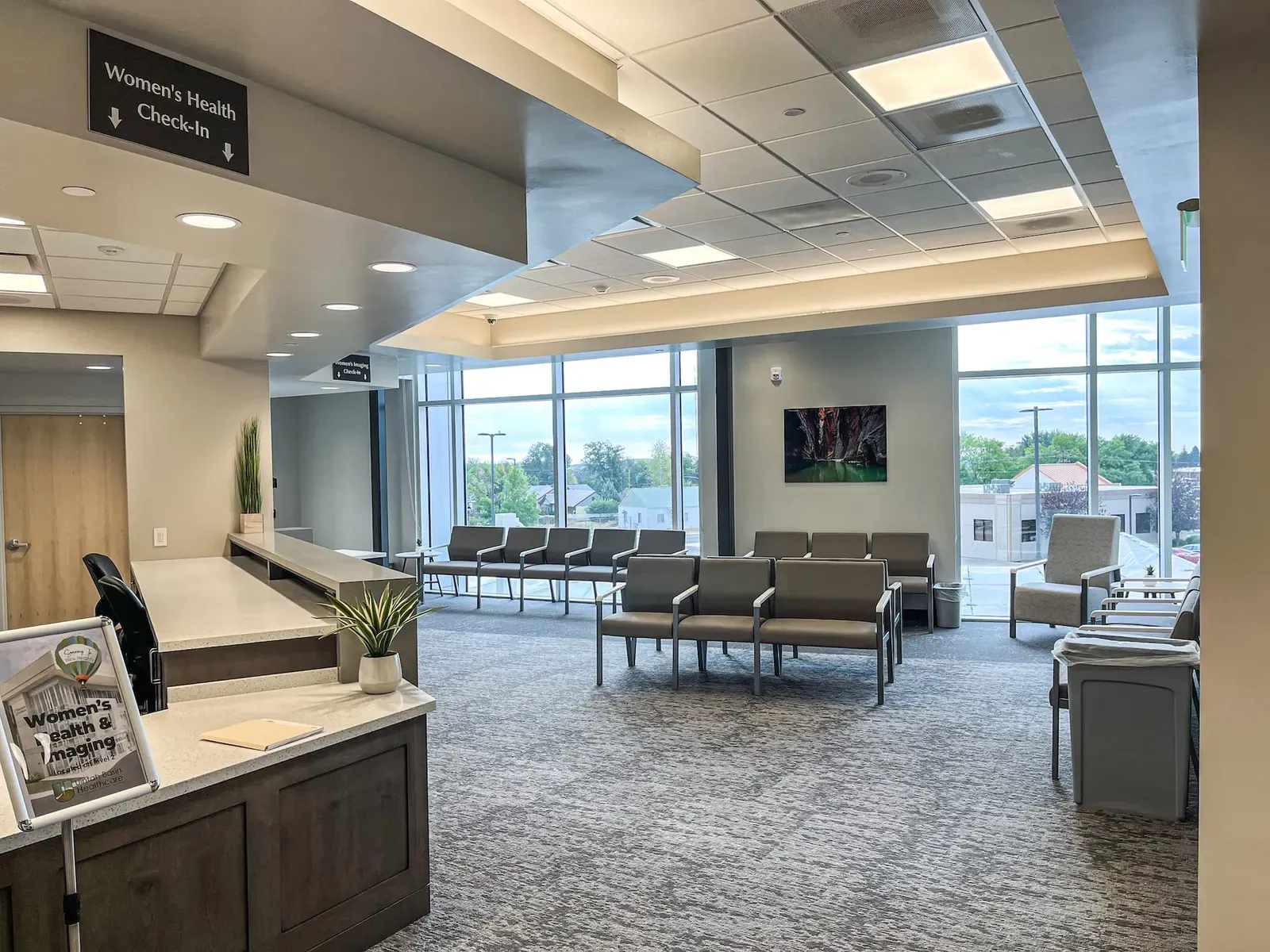 Women's Health check-in desk and waiting area with gray chairs and large windows