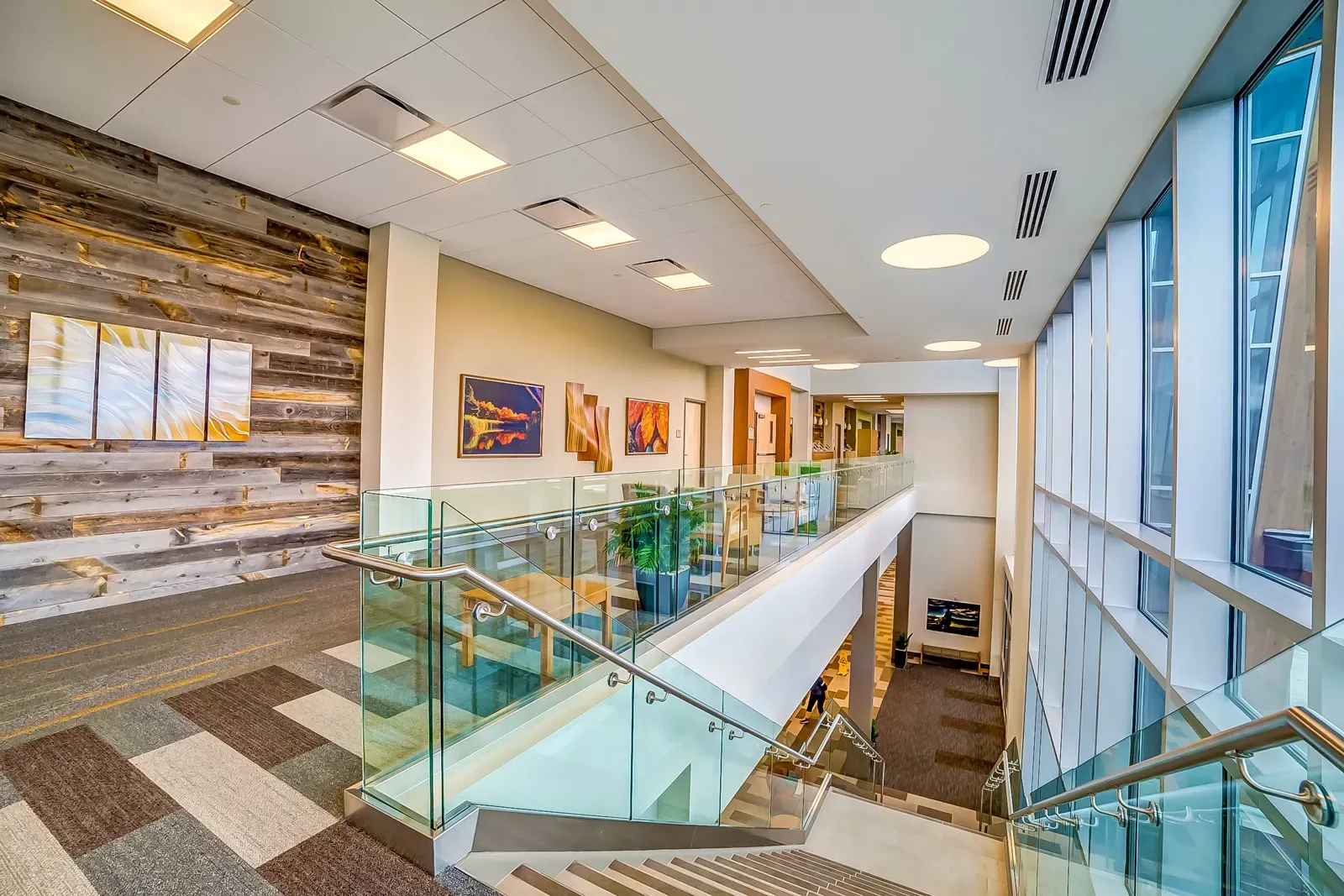 Open stairwell with glass railings, a reclaimed-wood feature wall and framed artwork.