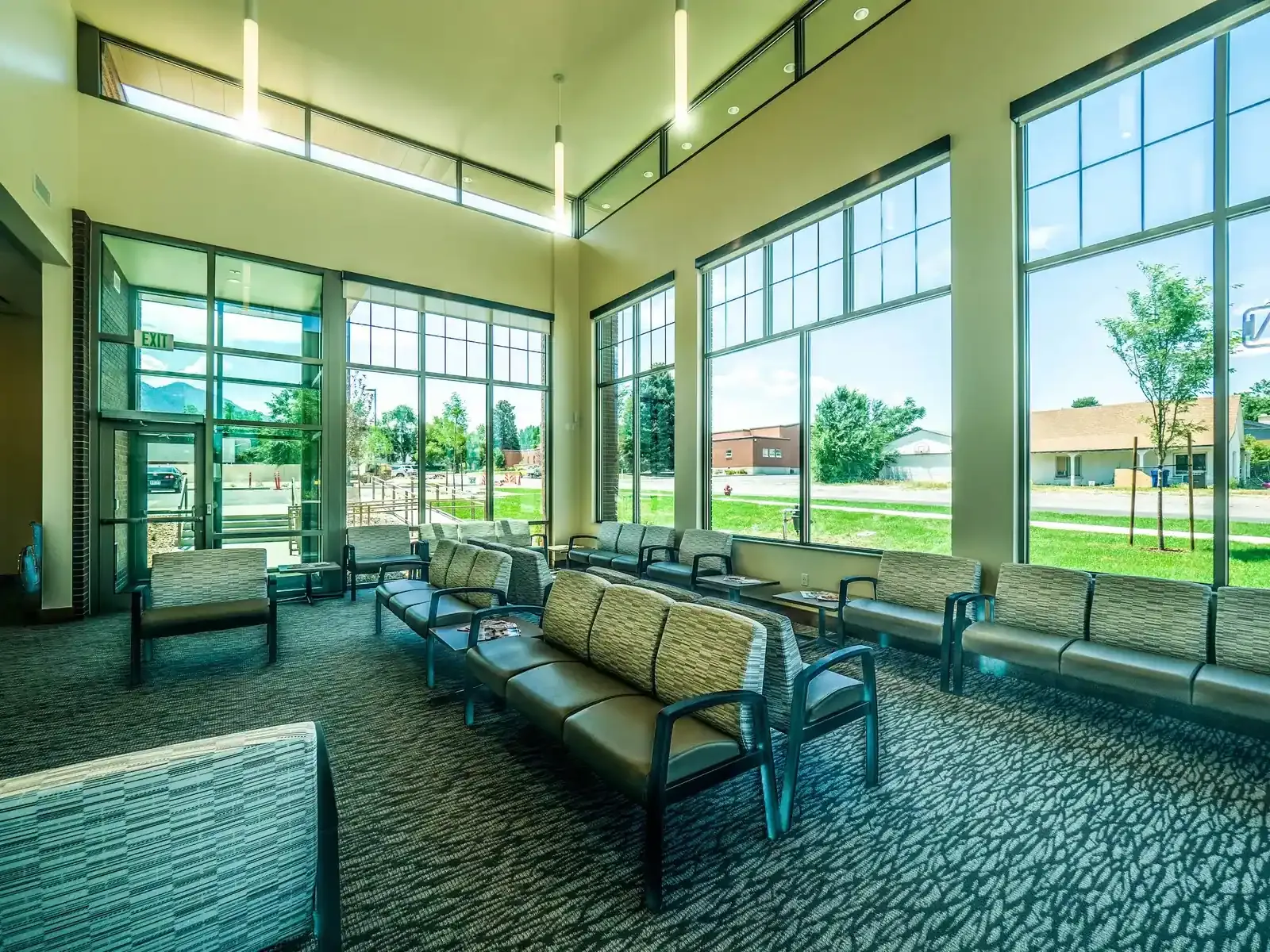Waiting area with cushioned seating, tall windows and patterned carpet.