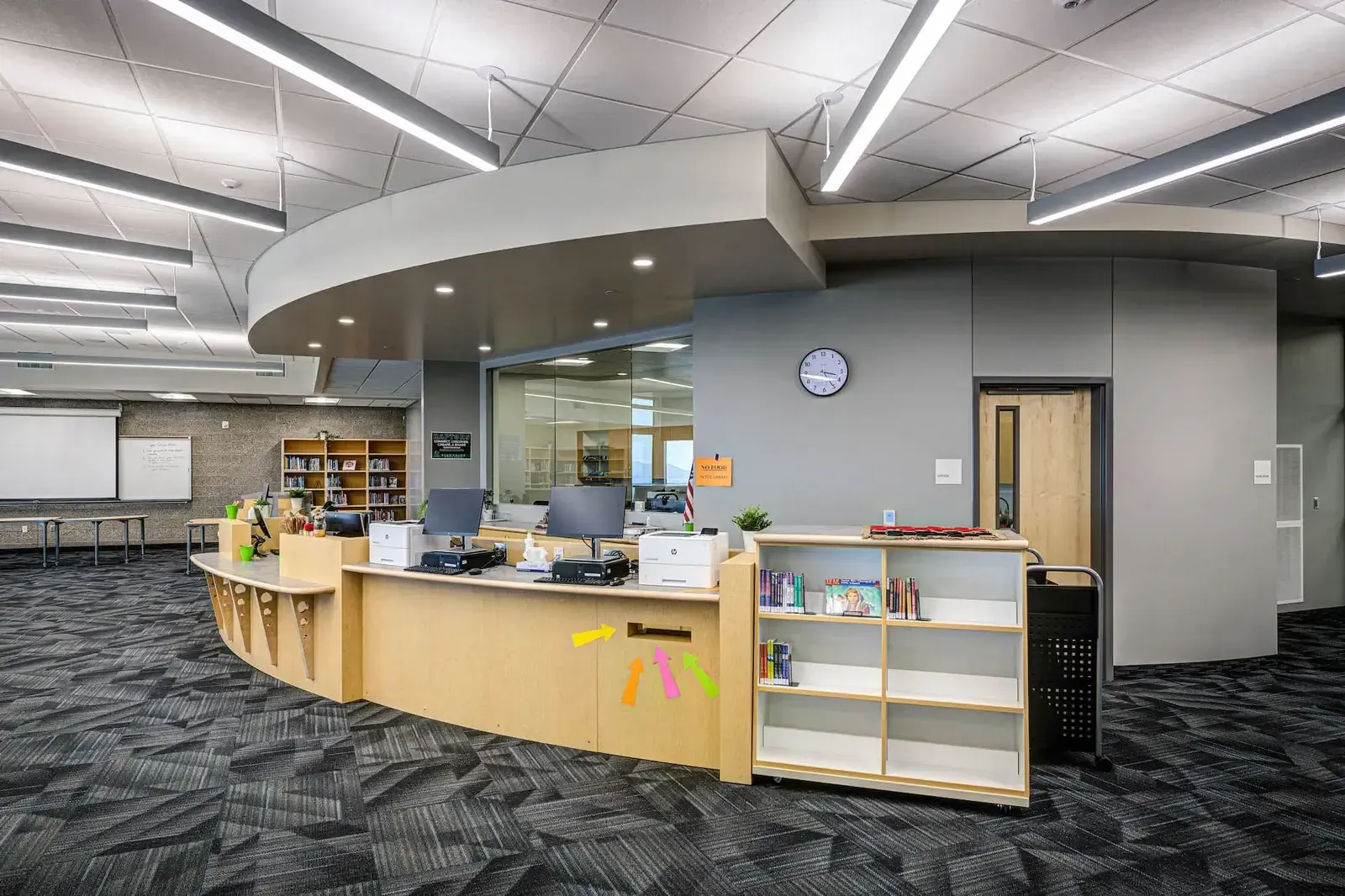 Media center circulation desk with a curved wood counter and bookshelves beyond.
