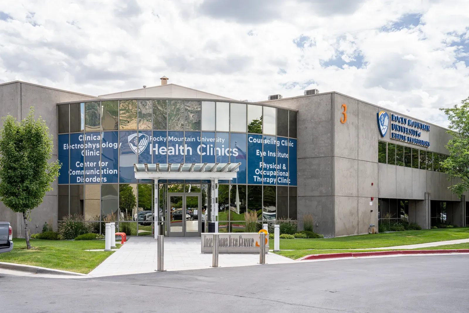 Exterior of Building 3 at Rocky Mountain University of Health Professions, with a glass entry and Health Clinics signage.
