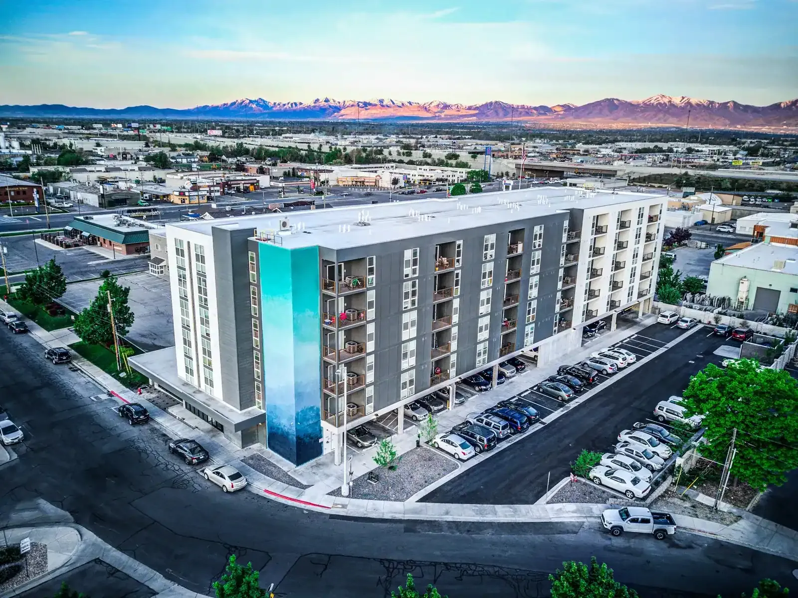 Aerial view of the apartment building and its side parking lot with mountains in the distance.