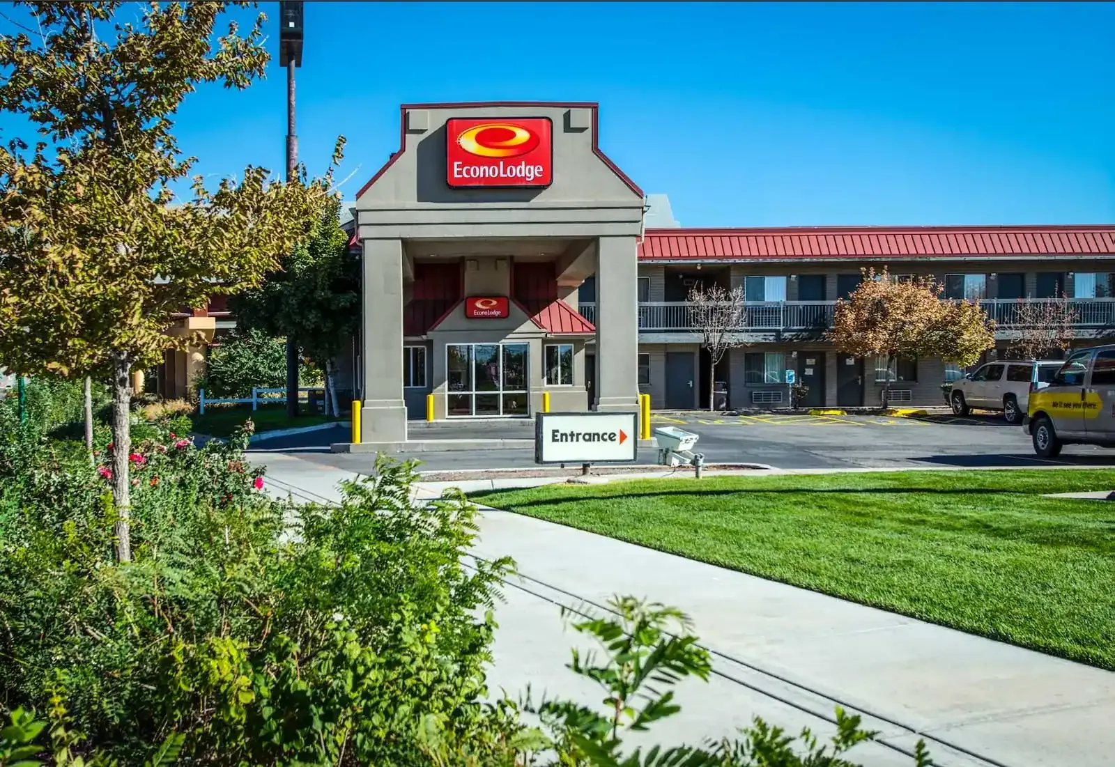 Motel entrance canopy with an Econo Lodge sign, an Entrance sign and a lawn in the foreground