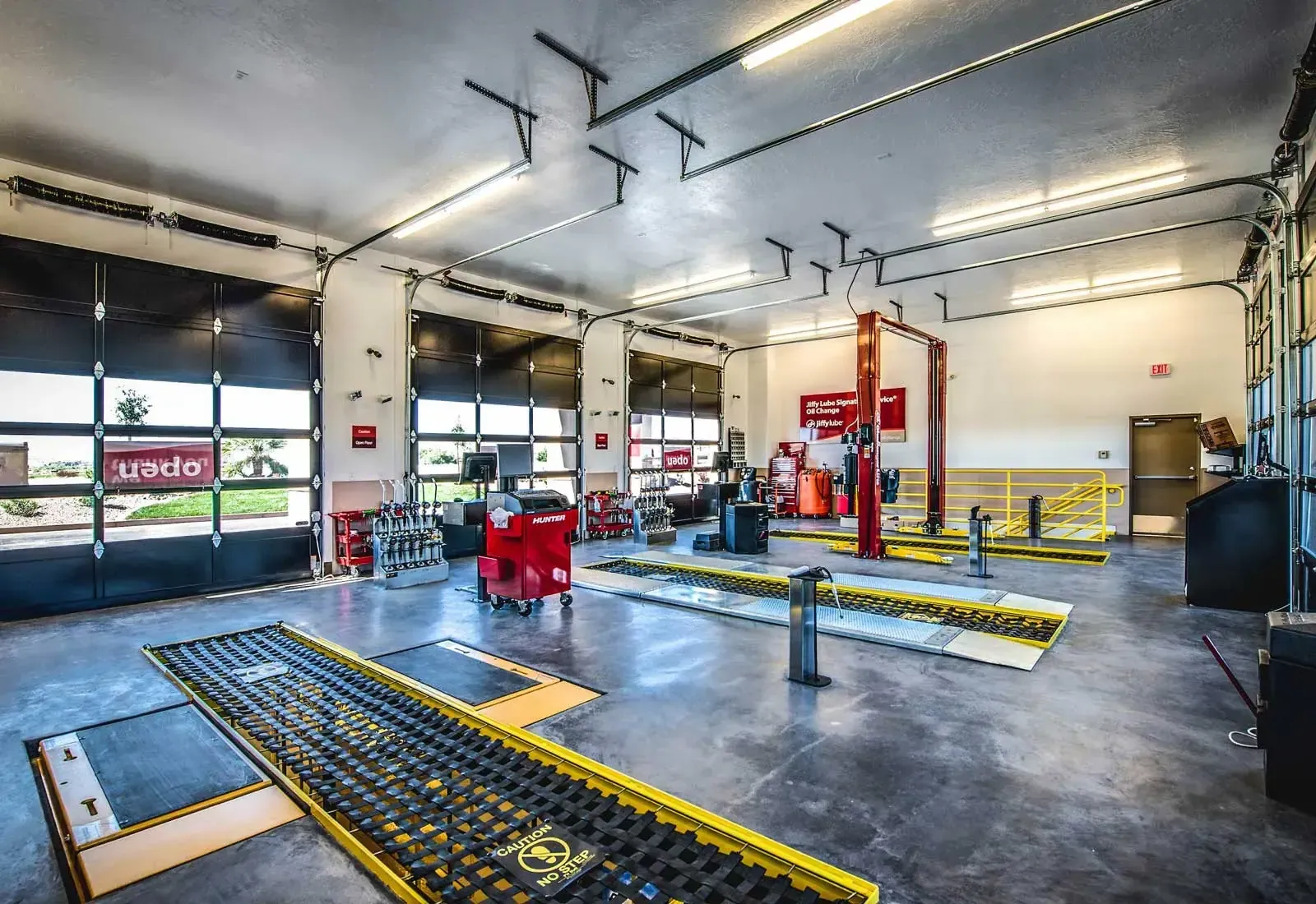 Service bay interior with floor grates, lift equipment and garage doors along one wall.