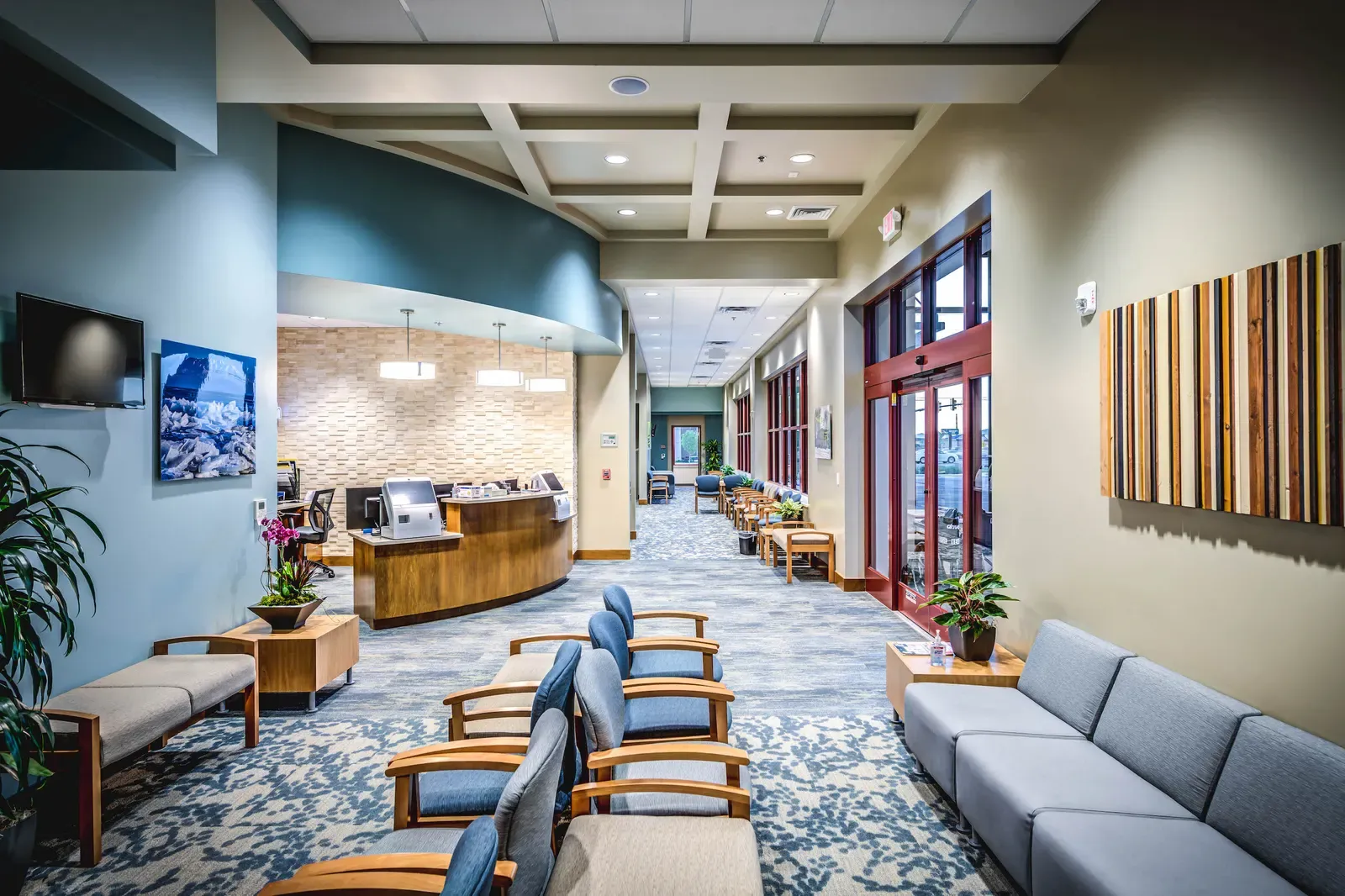 Waiting area with a curved reception desk, upholstered chairs and a tall window wall.