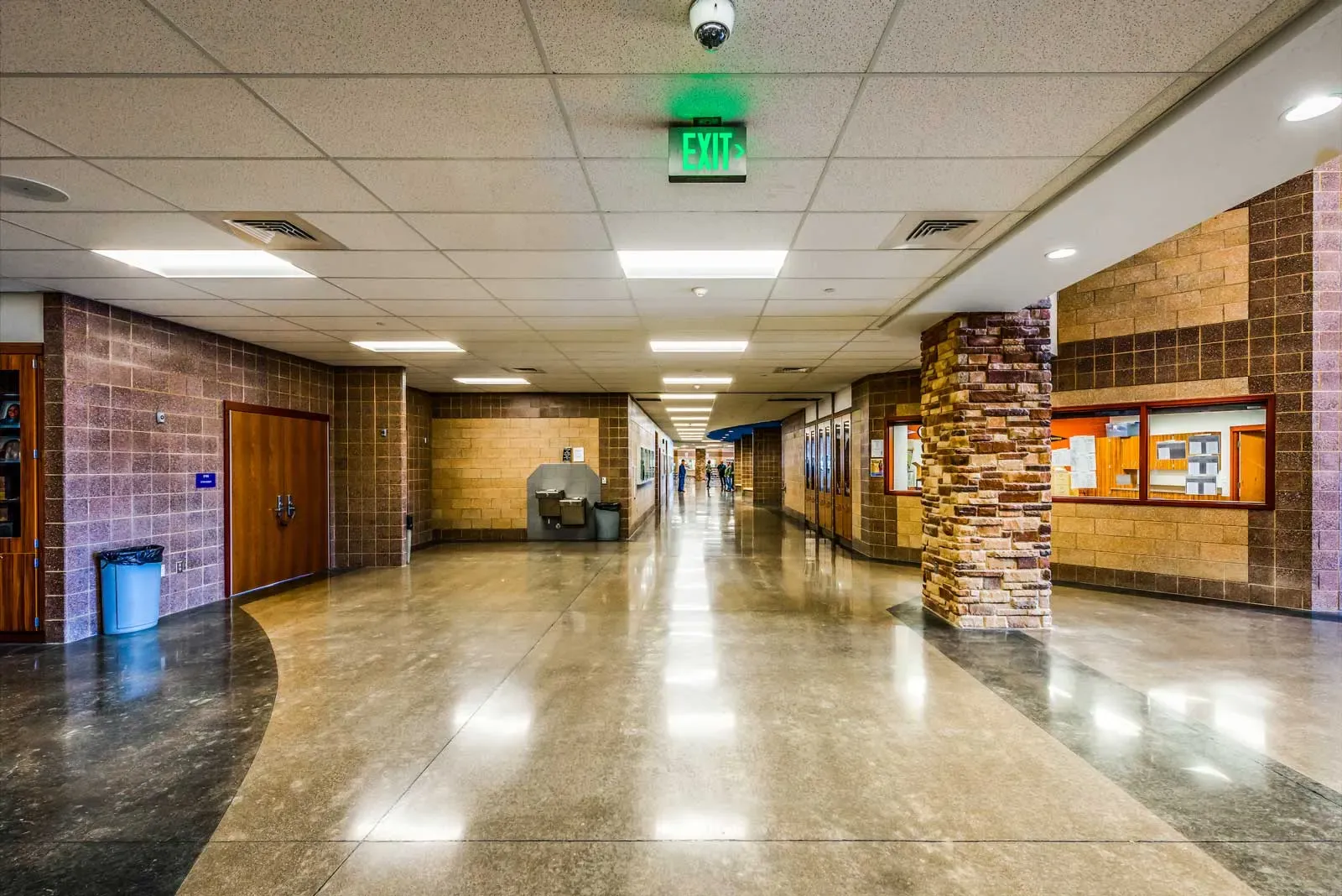 Main hallway with a polished concrete floor, brick walls, a stone-clad column and wood doors