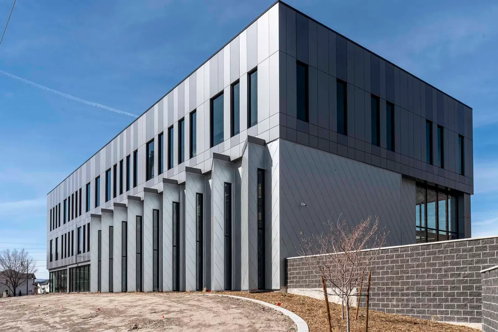 Corner of the three-story building clad in dark gray metal panels with vertical fins.