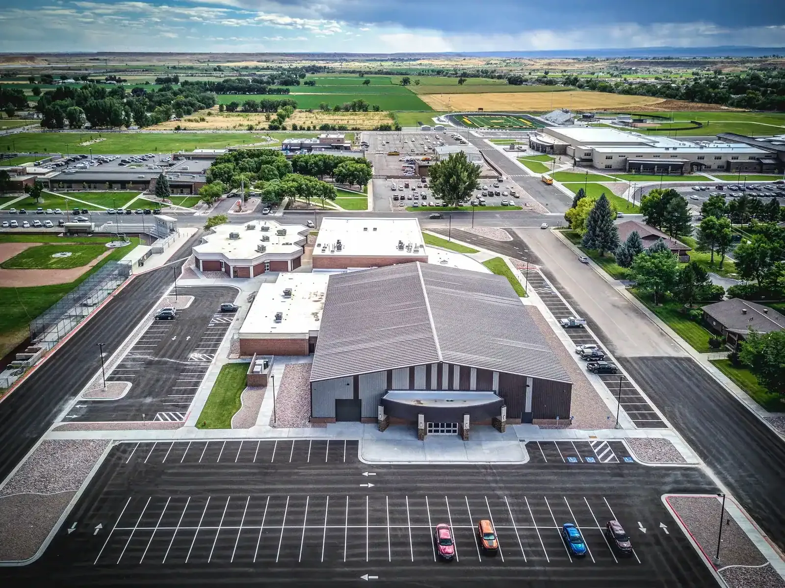 Aerial view of the metal-roofed training building and surrounding parking lots, with farmland beyond