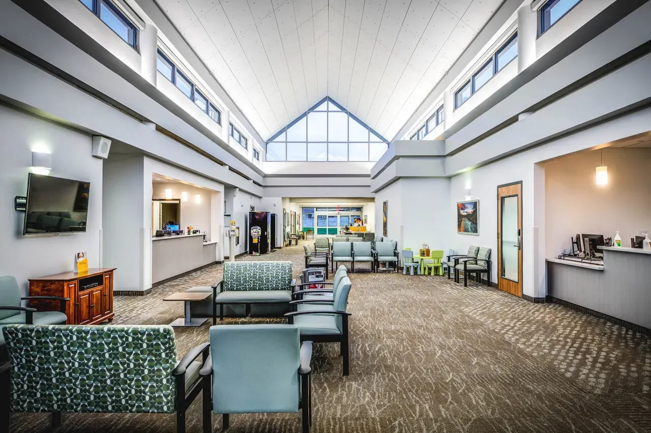 Waiting area under a tall gabled skylight with clinic seating and a check-in counter at the back.