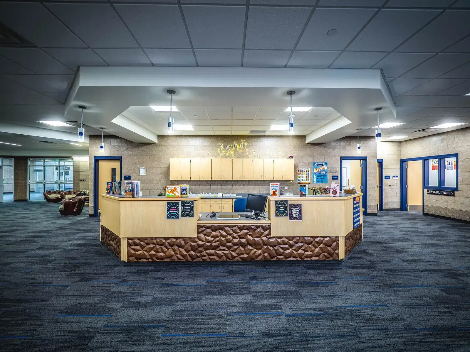 Open lobby with a wood-and-stone-textured reception counter and blue carpet