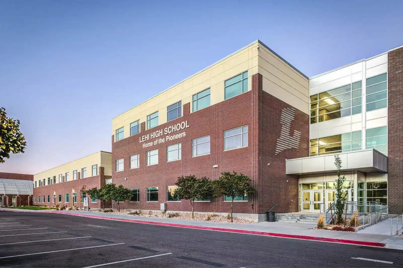Front of the three-story brick school with the Lehi High School sign and a glass entry.