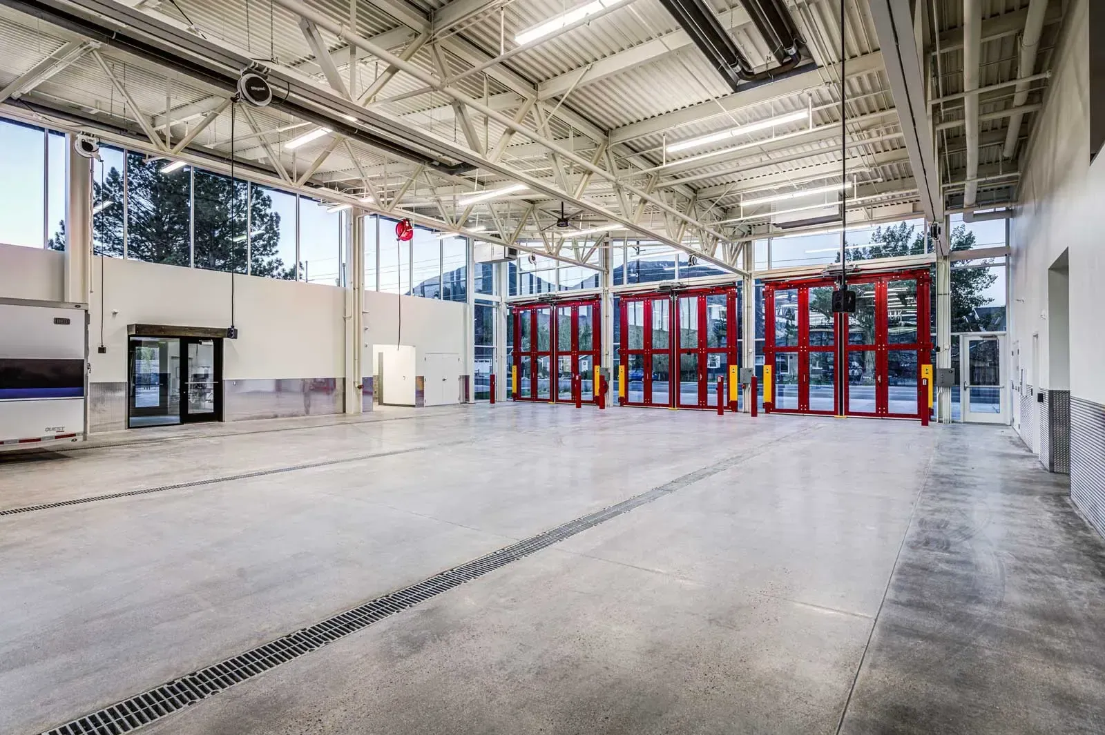 Apparatus bay with a polished concrete floor, steel trusses and red bay doors.