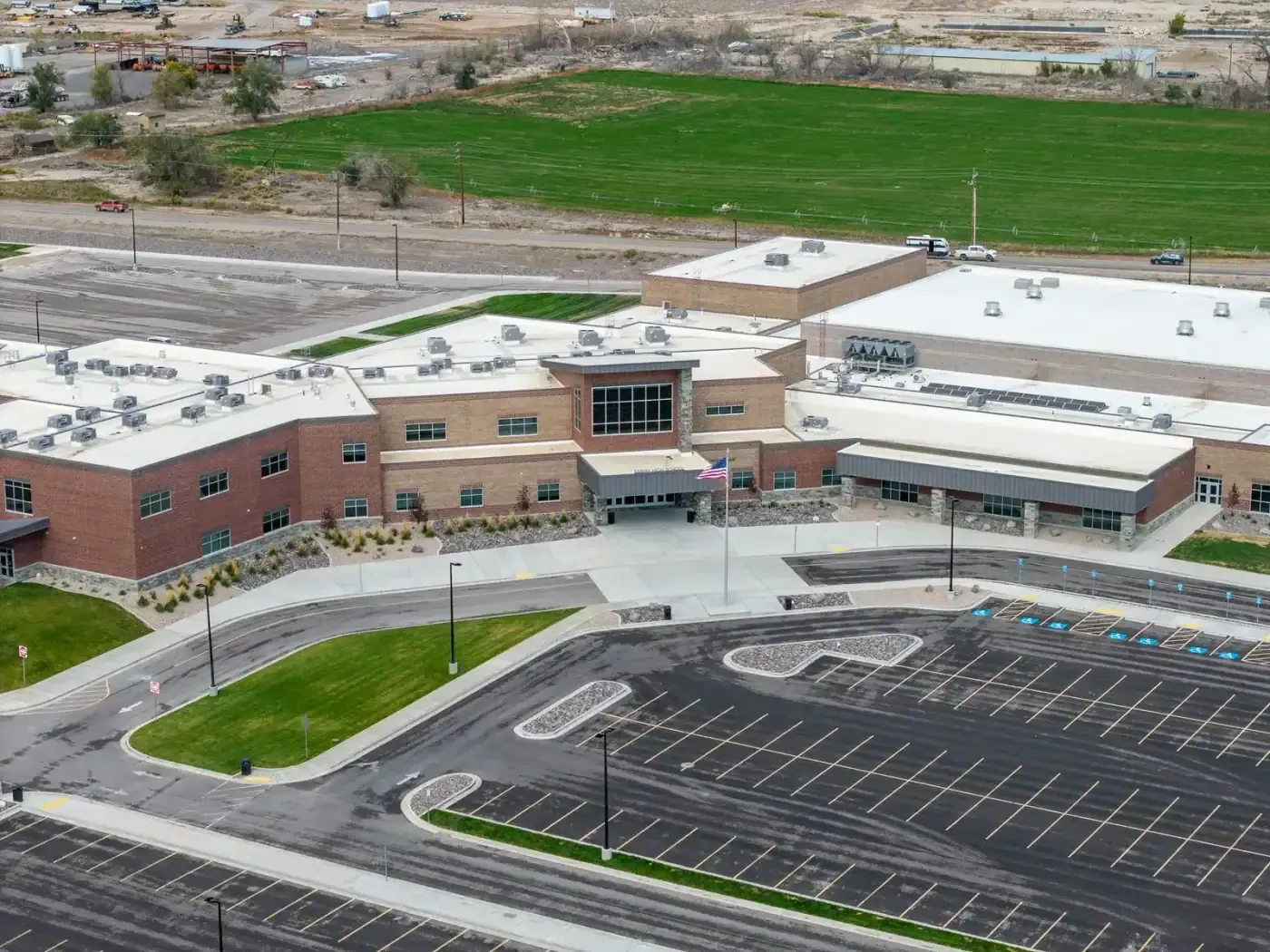 Aerial view of the school's brick building and entrance canopy beside a parking lot and farm fields.