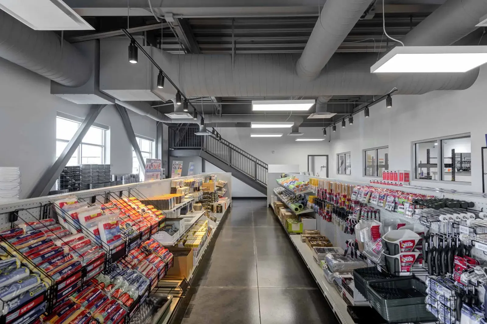 Paint aisle with shelves of paint rollers and brushes under exposed ductwork