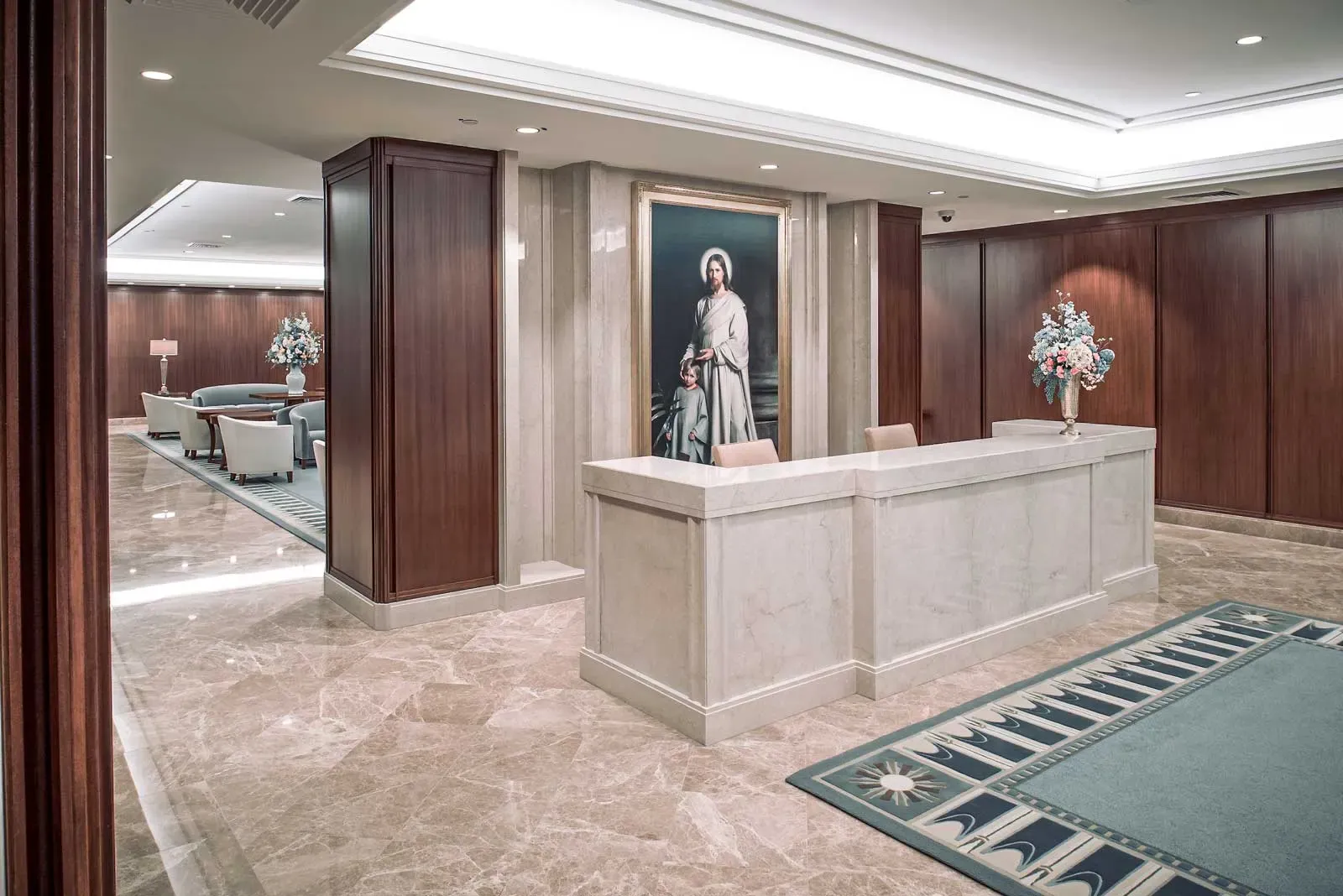 Reception lobby with a marble-fronted desk, wood-paneled walls, and a framed painting of a robed figure