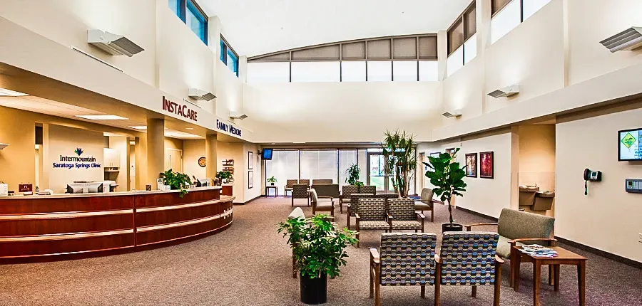 Lobby with a curved wood reception counter, InstaCare and Family Medicine signs, a tall ceiling with clerestory windows and a waiting area