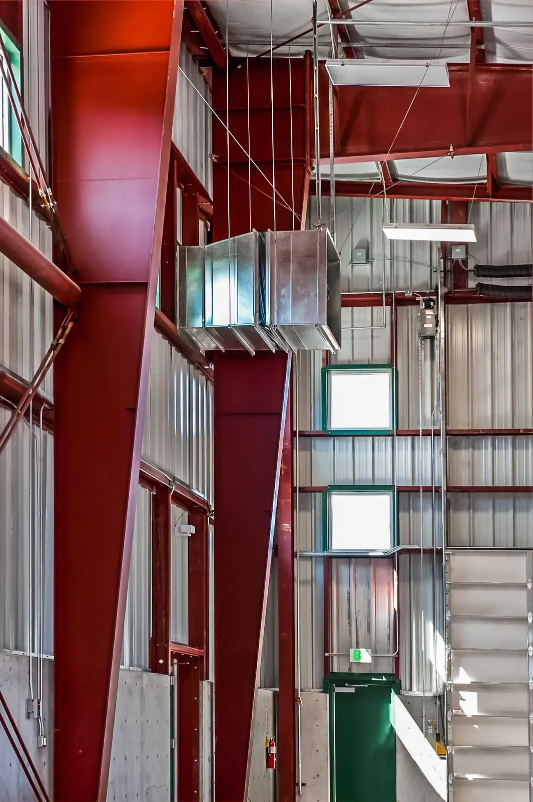 Warehouse interior showing red steel columns and beams, metal wall panels, and a green door