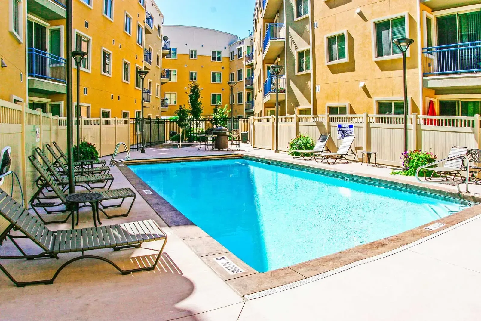 Courtyard swimming pool surrounded by lounge chairs and multistory condominium buildings