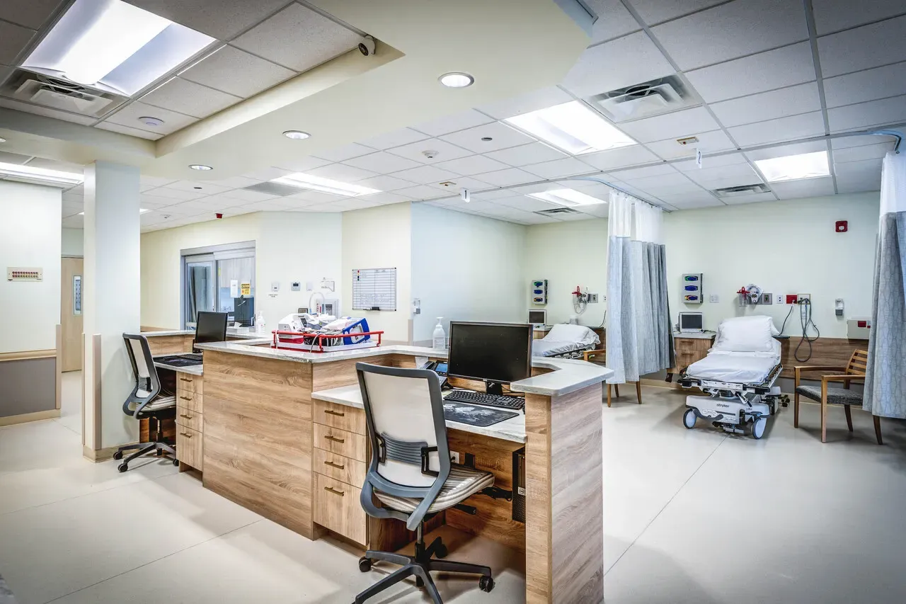 Nurses' station with wood-look cabinets and curtained patient bays behind it.