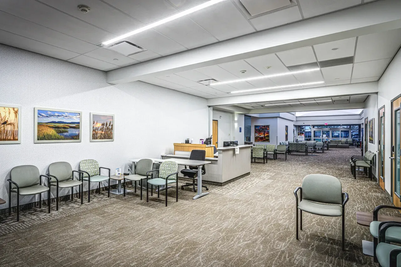 Long waiting area with a reception counter and framed landscape art on the wall.