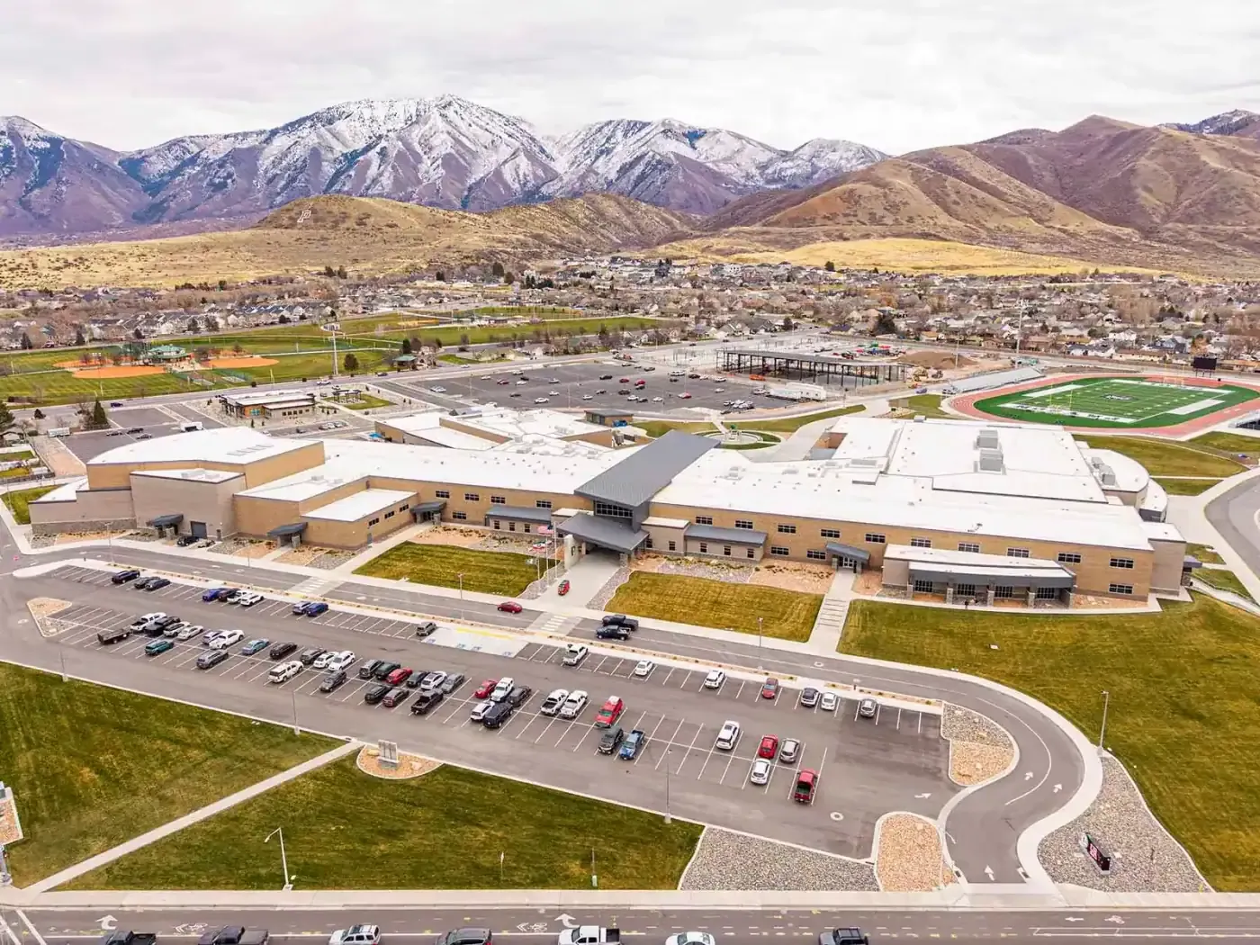 Aerial view of the school, its parking lots and football field with mountains behind