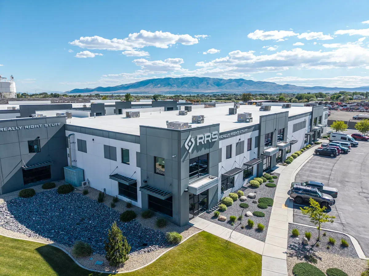 Close aerial view of the building corner with a lettered sign, rock landscaping and a parking lot.