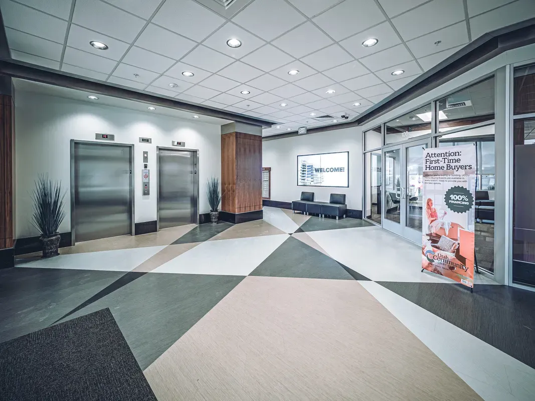Elevator lobby with a diamond-patterned floor and a welcome monitor on the wall