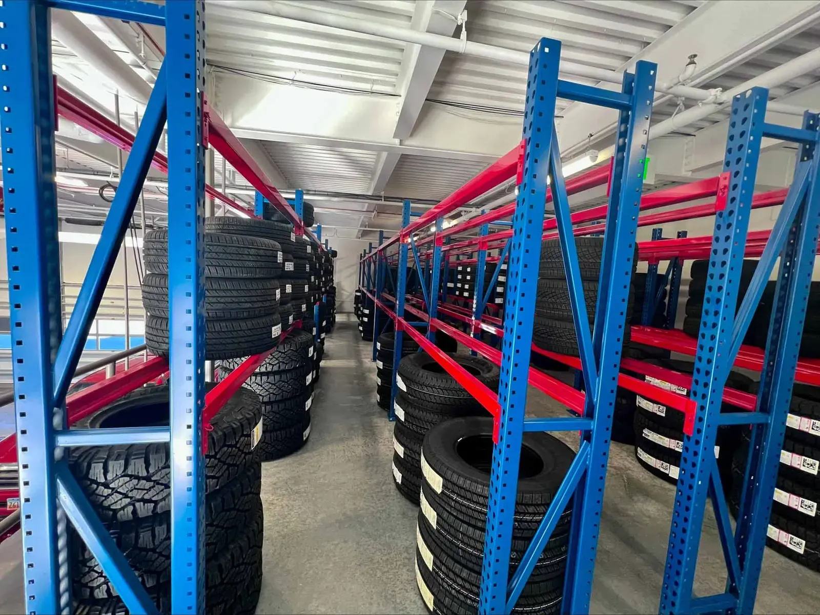 Rows of blue and red steel racks stocked with tires