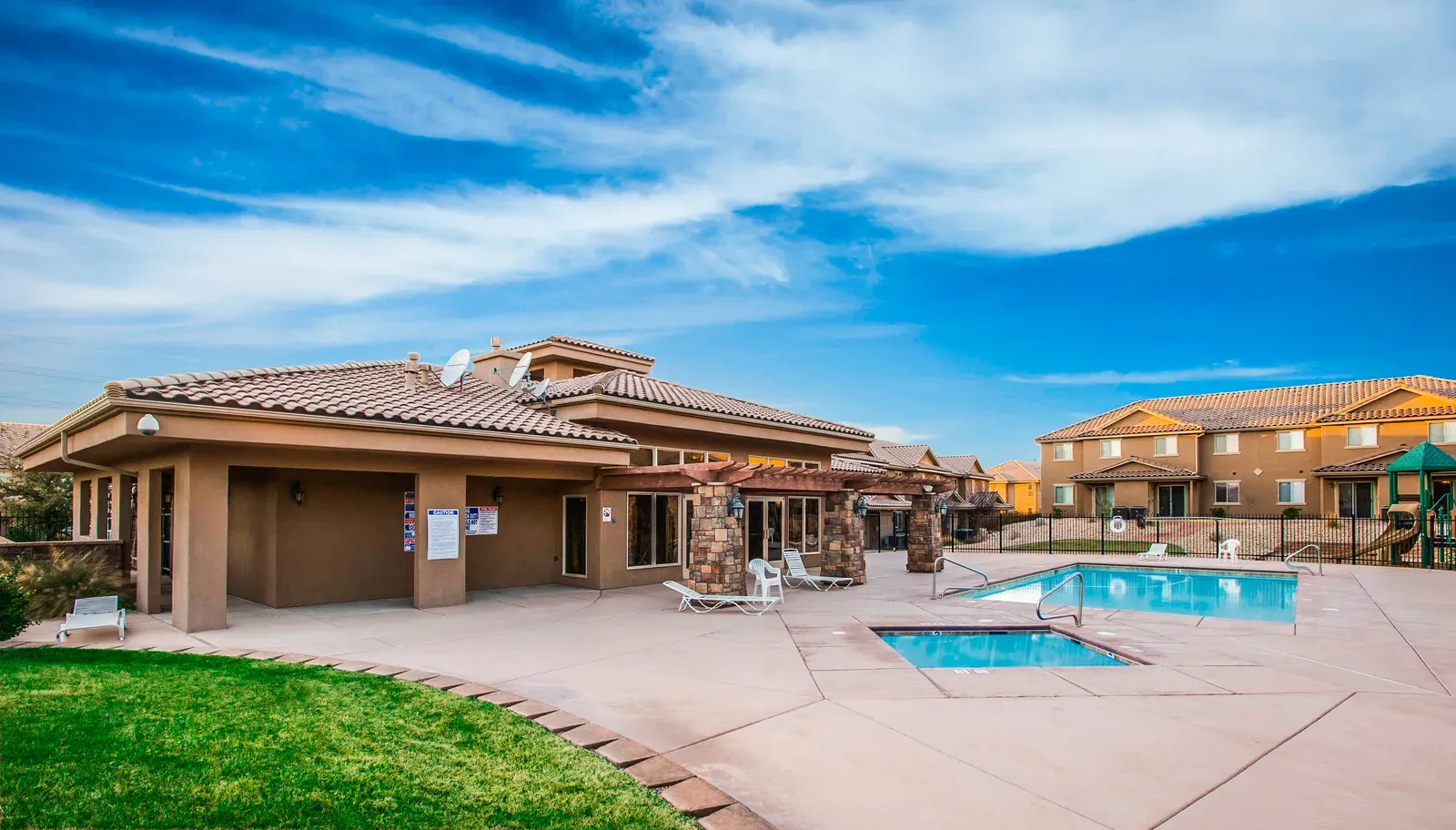 Clubhouse patio with a swimming pool and hot tub, with townhomes beyond the fence