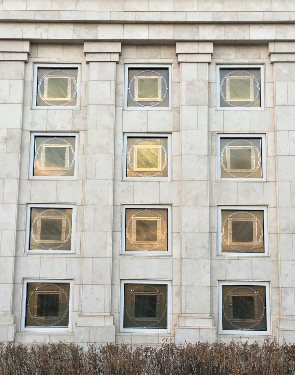 Close view of the temple's stone wall with rows of windows holding circle-and-square art glass.