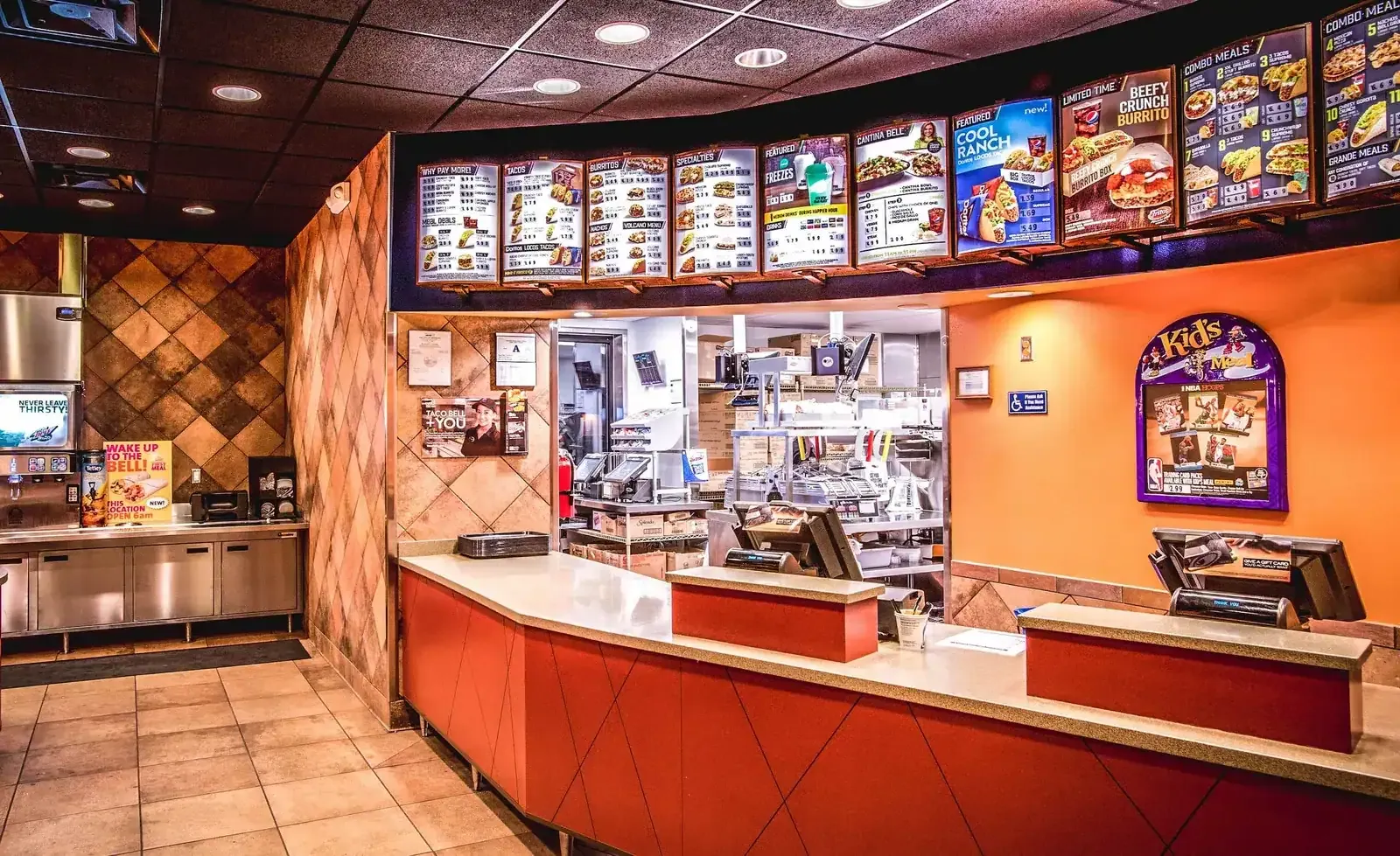 Service counter with overhead menu boards, a kids meal sign and a drink station