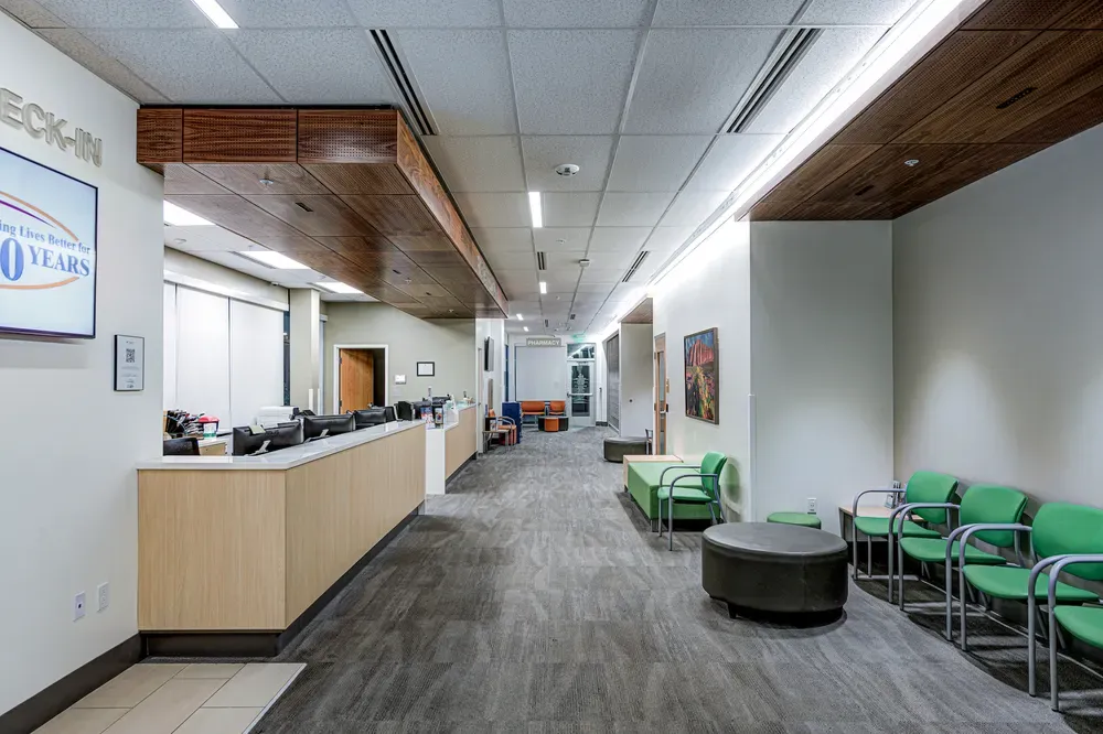 Check-in counter and waiting area with green chairs under a wood-paneled ceiling.