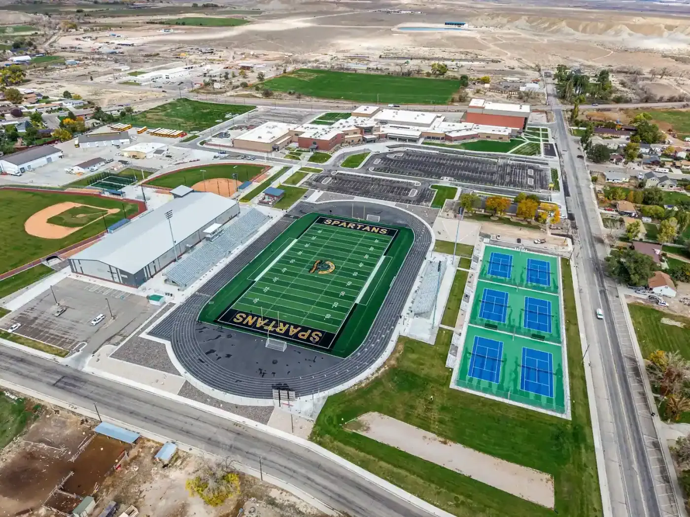 Aerial view of the school campus in Castle Dale with a football stadium, tennis courts and parking lots.