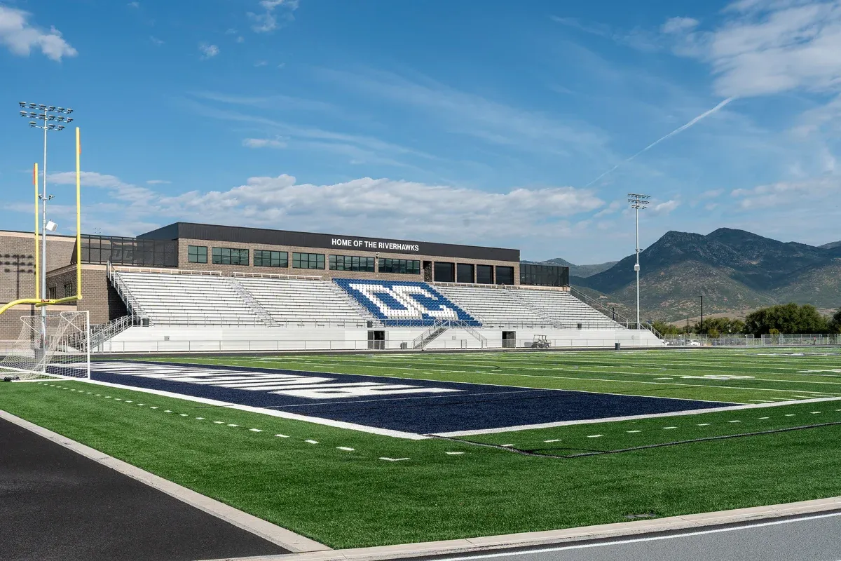 Football stadium with a navy end zone, home grandstand, and mountains beyond