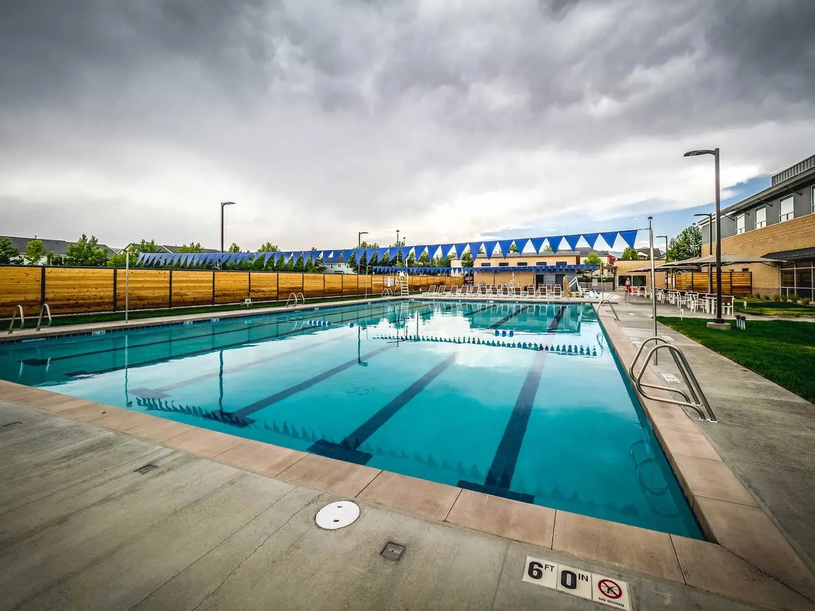 Outdoor pool with lane lines, blue pennant banners and a wood fence.