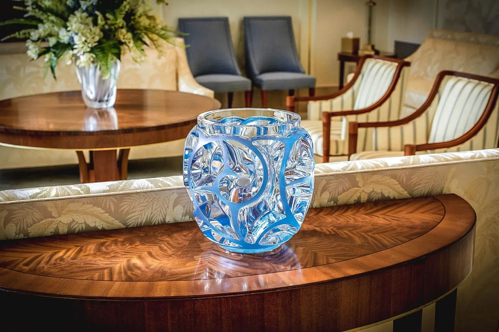 Blue and clear glass vase on a wood table in a sitting room.