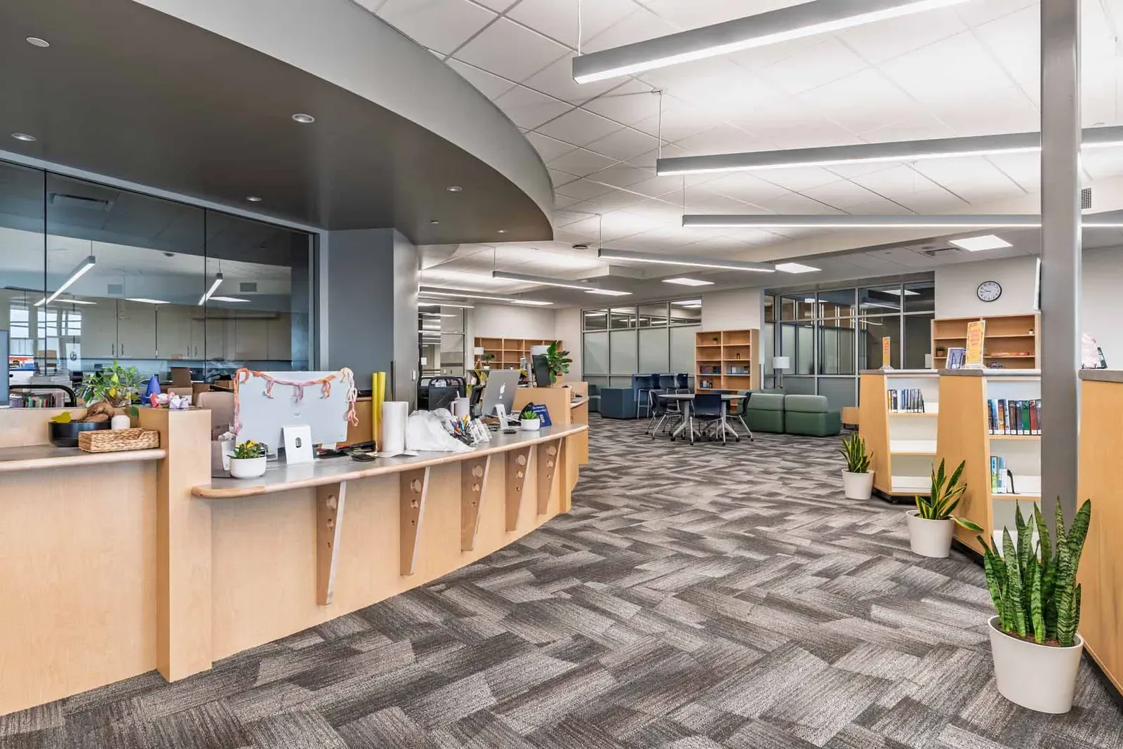 Bright open room with a curved wood service desk, bookshelves and patterned carpet.