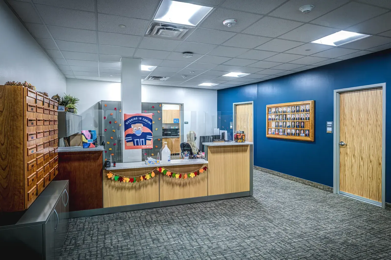 Reception desk with wood mailboxes beside a blue accent wall and a wood door