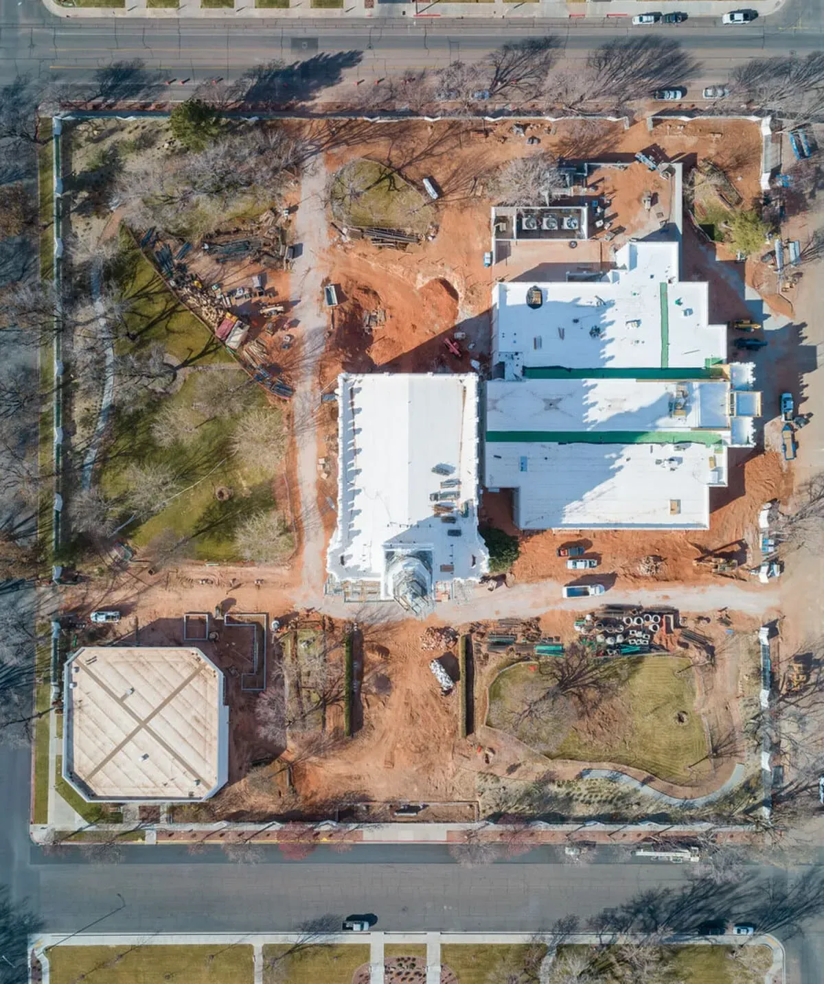 Overhead view of the temple site during construction, with white roofs and bare dirt around the building.