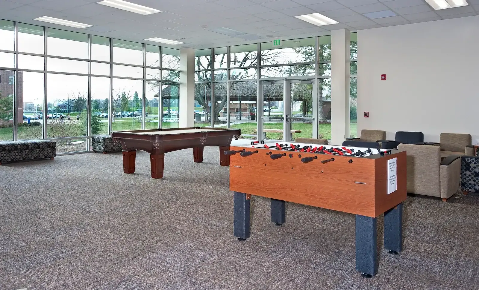 Game room with a pool table and a foosball table beside a wall of windows.