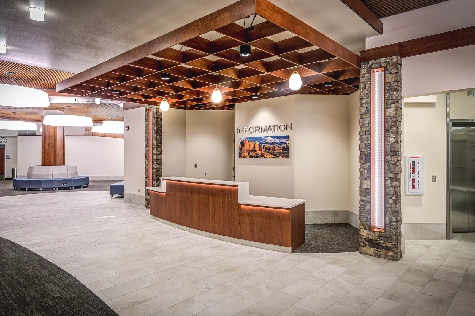 Main lobby with a curved wood information desk, a coffered wood-beam ceiling and stone-clad columns