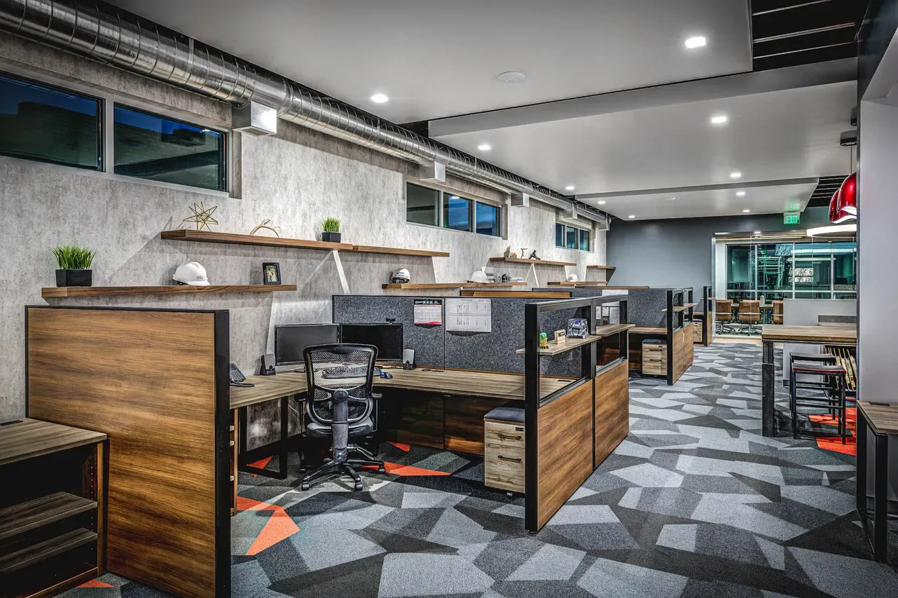 Open office area with wood-faced workstations and angular patterned carpet